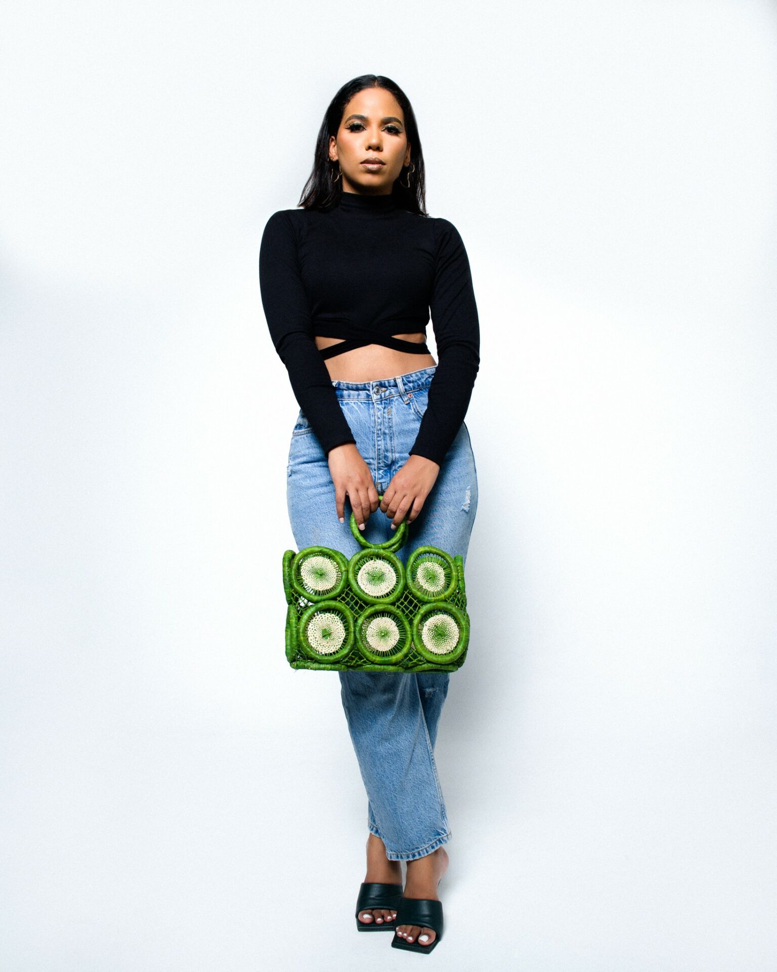 A GLOWBE model holding a bright green woven artisan bag